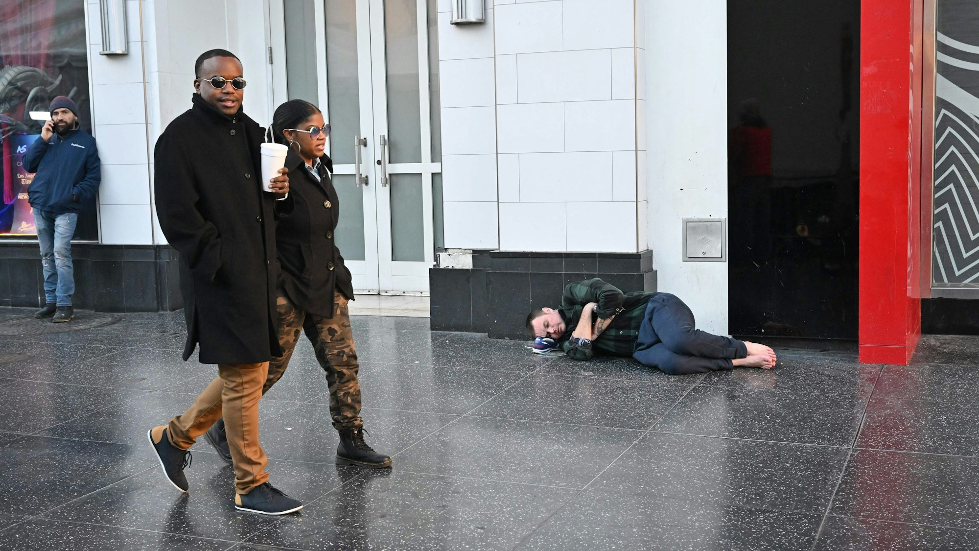 Ein Mann stützt seinen Kopf auf seine Schuhe, während er am Hollywood Boulevard in Los Angeles schläft.