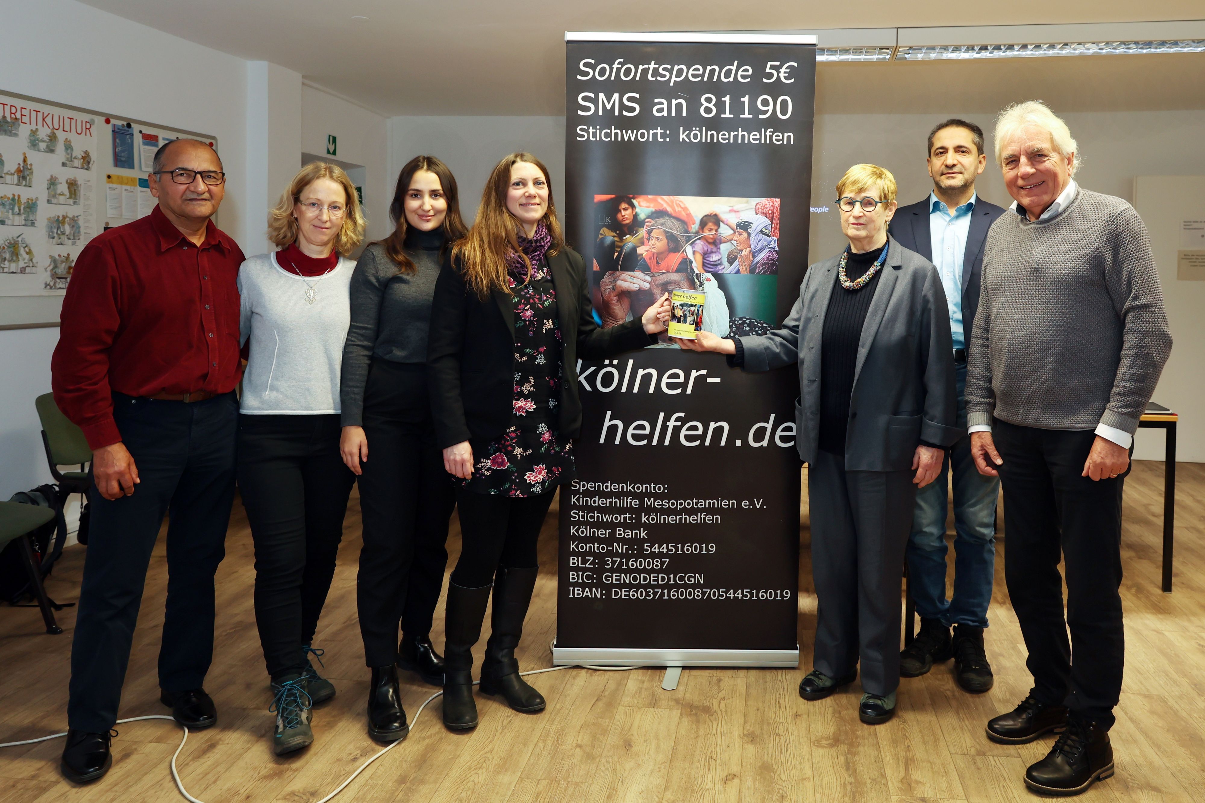 Ali Gececi, Dorothee Zimmer- Gececi, Anna Gececi, Berit Kranz, Anke Brunn, Vedat Akfer und Jürgen Roters
stehen neben einem Aufsteller mit einem Spendenaufruf.