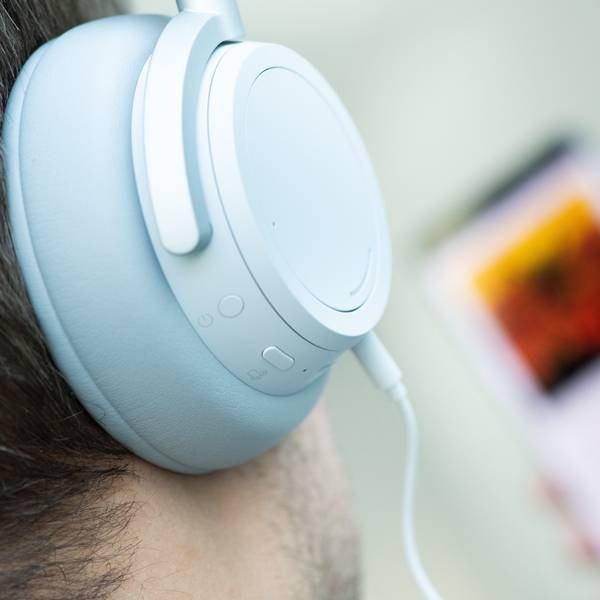 Ein junger Mann hört mit Kopfhörern Musik.