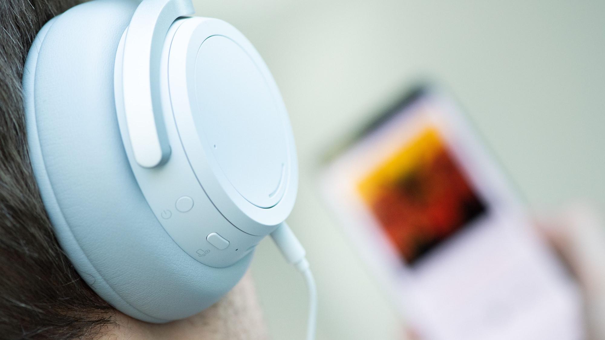 Ein junger Mann hört mit Kopfhörern Musik.