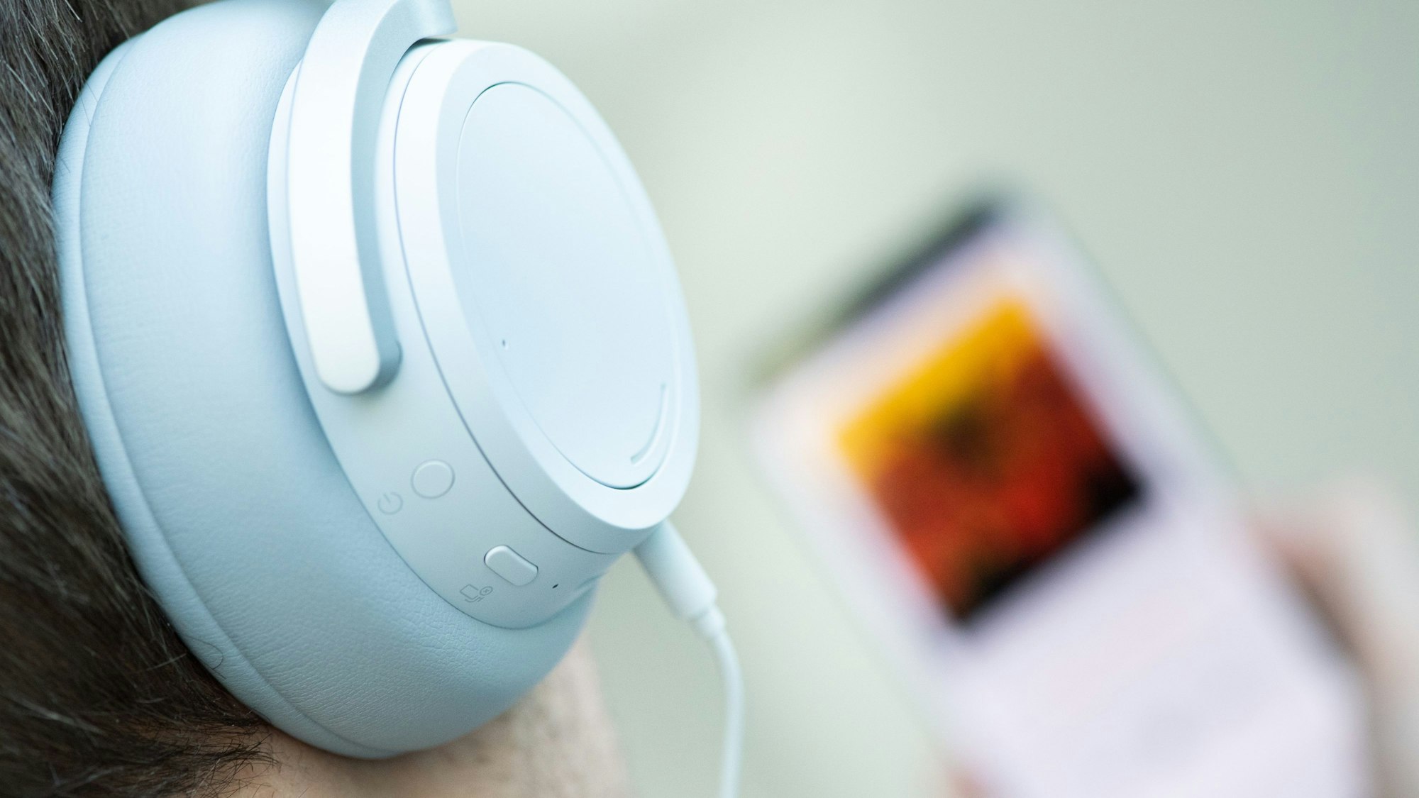 Ein junger Mann hört mit Kopfhörern Musik.