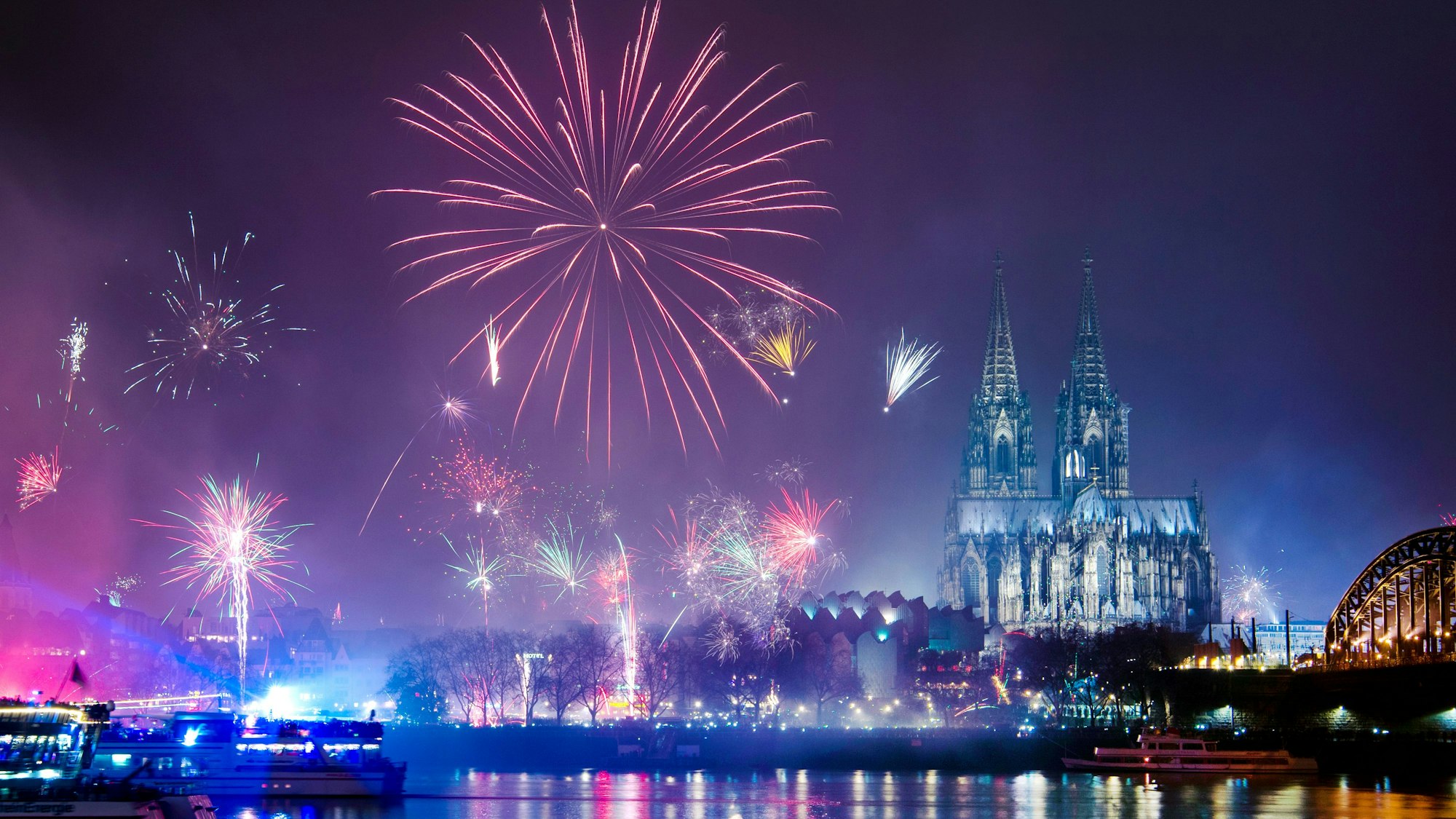 Feuerwerk ist in der Silvesternacht am Rhein über dem Dom zu sehen.