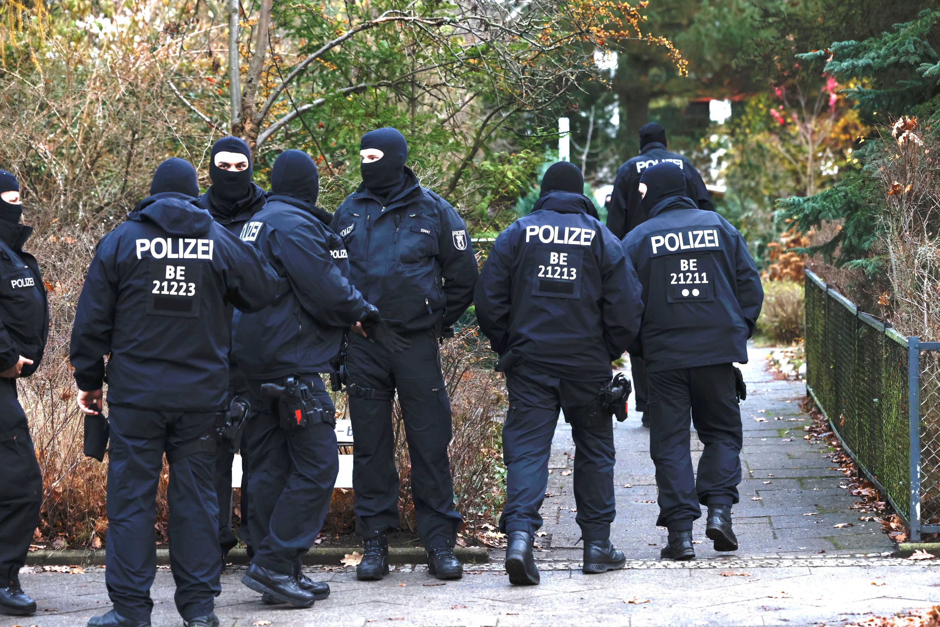 Vermummte Polizisten sind während der Razzia im „Reichsbürger“-Milieu in Berlin zu sehen, sie stehen vor einem Garteneingang.