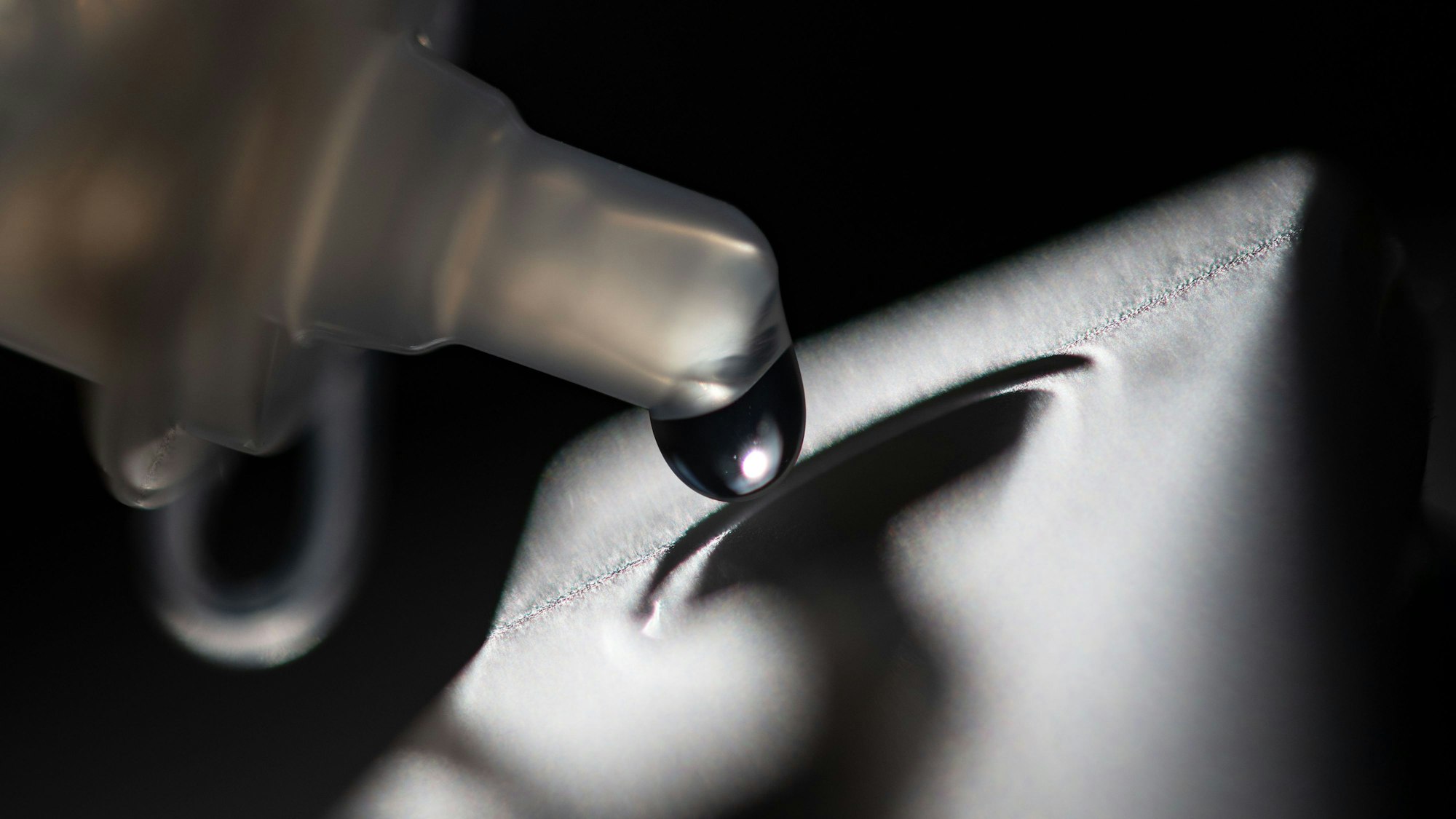 Ein Tropfen hängt am Röhrchen eines Corona-Antigen-Testkits.