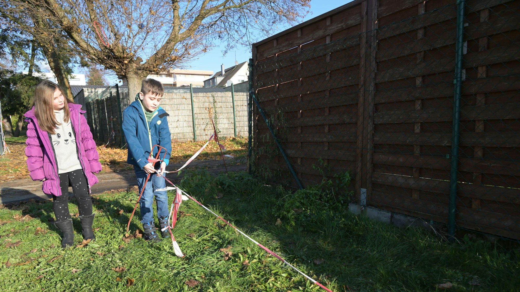Zwei Kinder stehen vor einem mit Flatterband abgesperrten Bereich.