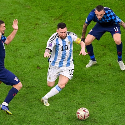 Argentiniens Superstar Lionel Messi dribbelt mit dem Ball durch das Mittelfeld, Kroatiens Mittelfeldstars Brozovic und Kovacic können nur staunend zuschauen.