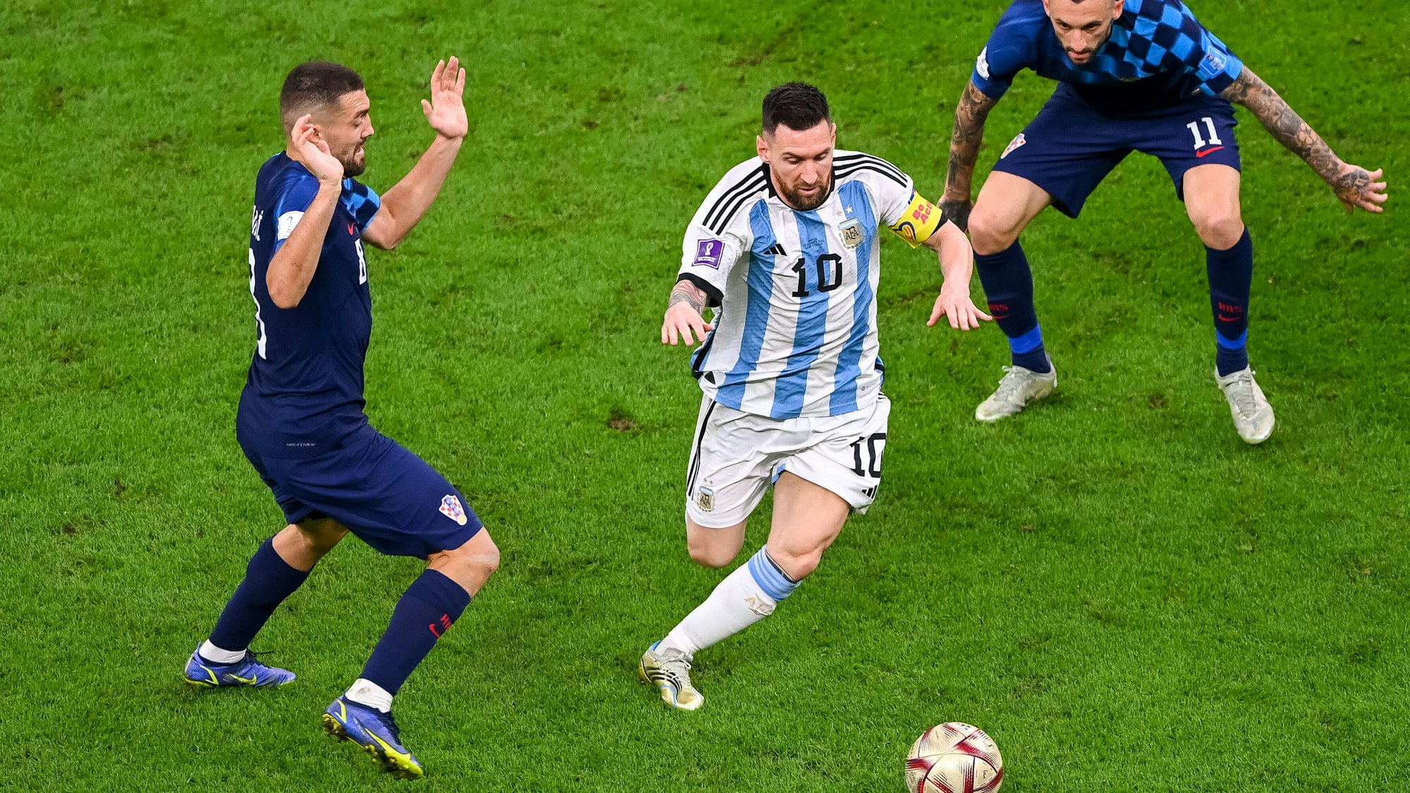 Argentiniens Superstar Lionel Messi dribbelt mit dem Ball durch das Mittelfeld, Kroatiens Mittelfeldstars Brozovic und Kovacic können nur staunend zuschauen.