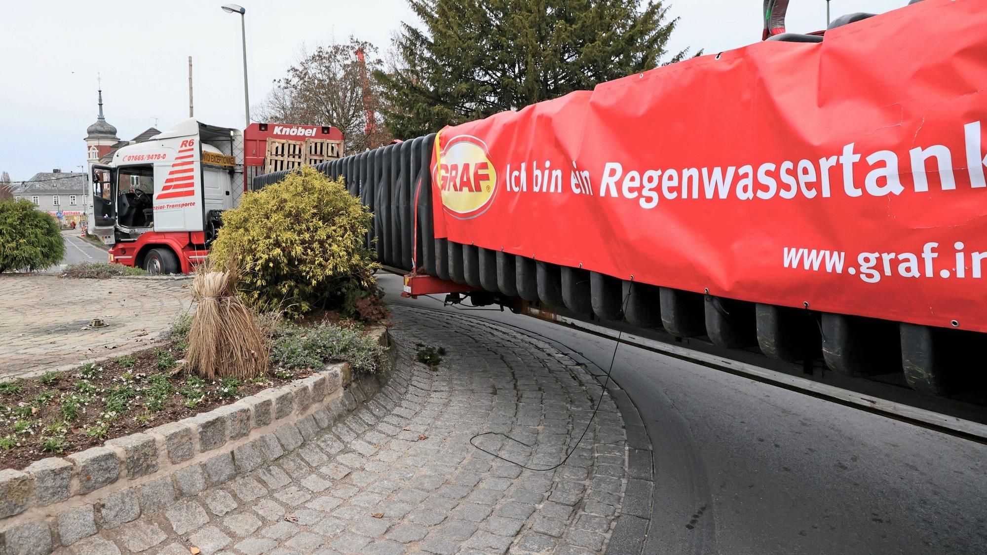 Der überlange Schwertransport schrammt am Brunnen-Kreisverkehr an der Mauer entlang und steckt fest.