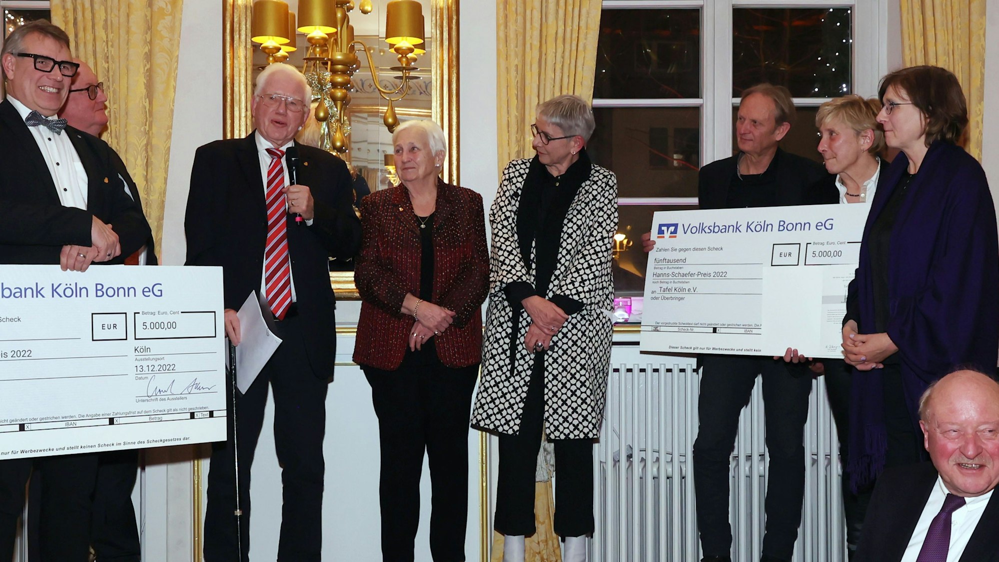 Das Bild zeigt Menschen auf einer Bühne, die zwei riesige Papierschecks überreicht bekommen.