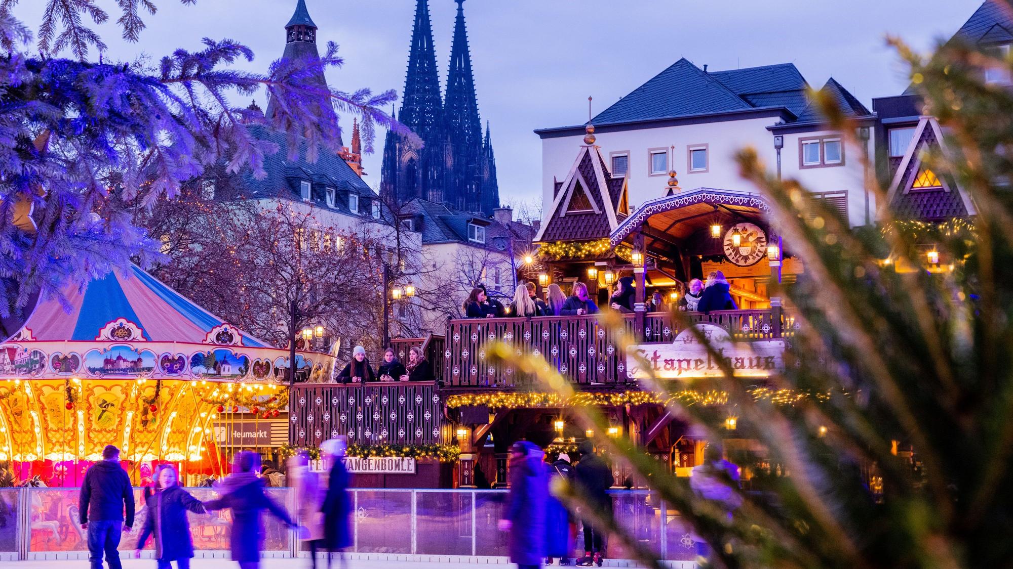 Besucher fahren auf einer Eisbahn auf dem Weihnachtsmarkt auf dem Heumarkt Schlittschuh.
