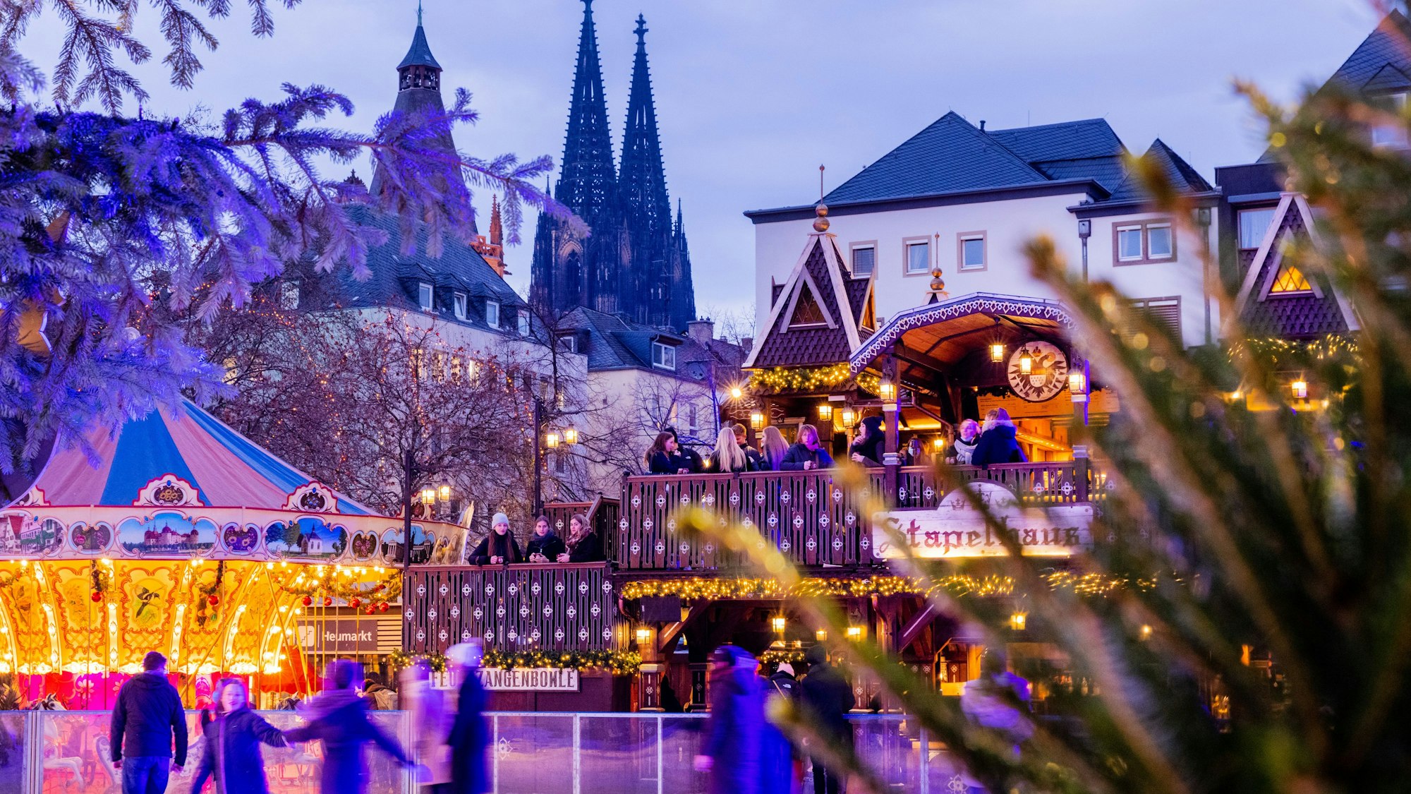 Besucher fahren auf einer Eisbahn auf dem Weihnachtsmarkt auf dem Heumarkt Schlittschuh.