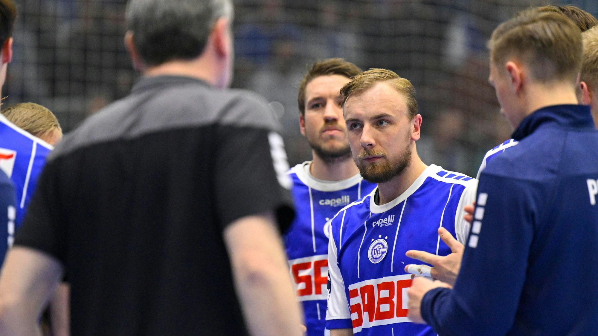 Einige Spieler des VfL Gummersbach stehen i Kreis zusammen, in der Mitte gut zu sehen ist Lukas Blohme.