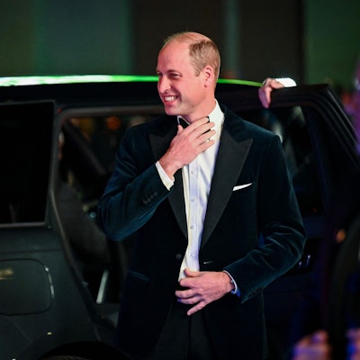 Prinz William mit Fliege und Anzug. Er grinst und steigt aus einem Auto.