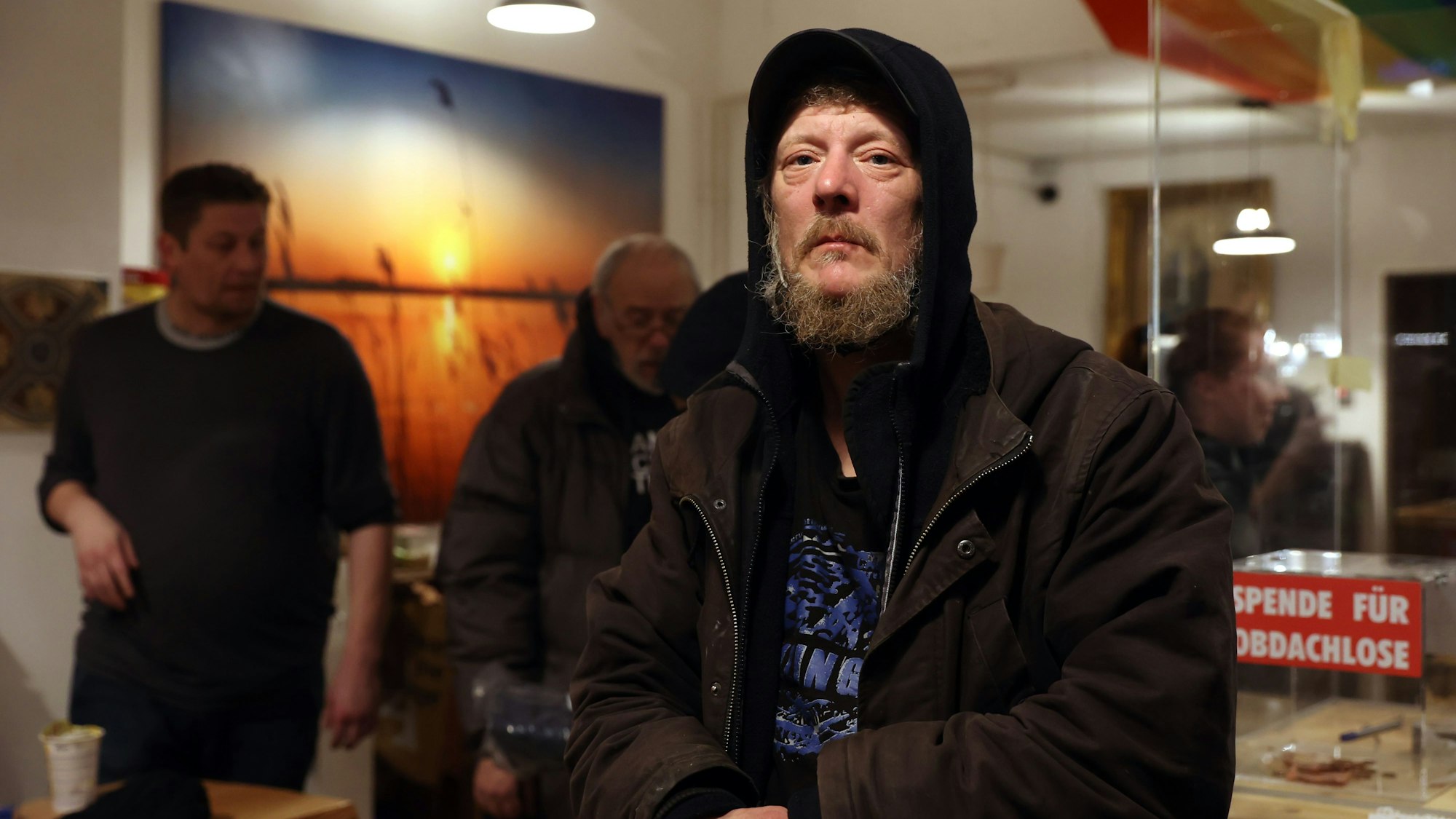 Ein Mann mit zotteligem Bart und Kapuze steht im Ladenlokal „Zohus“.