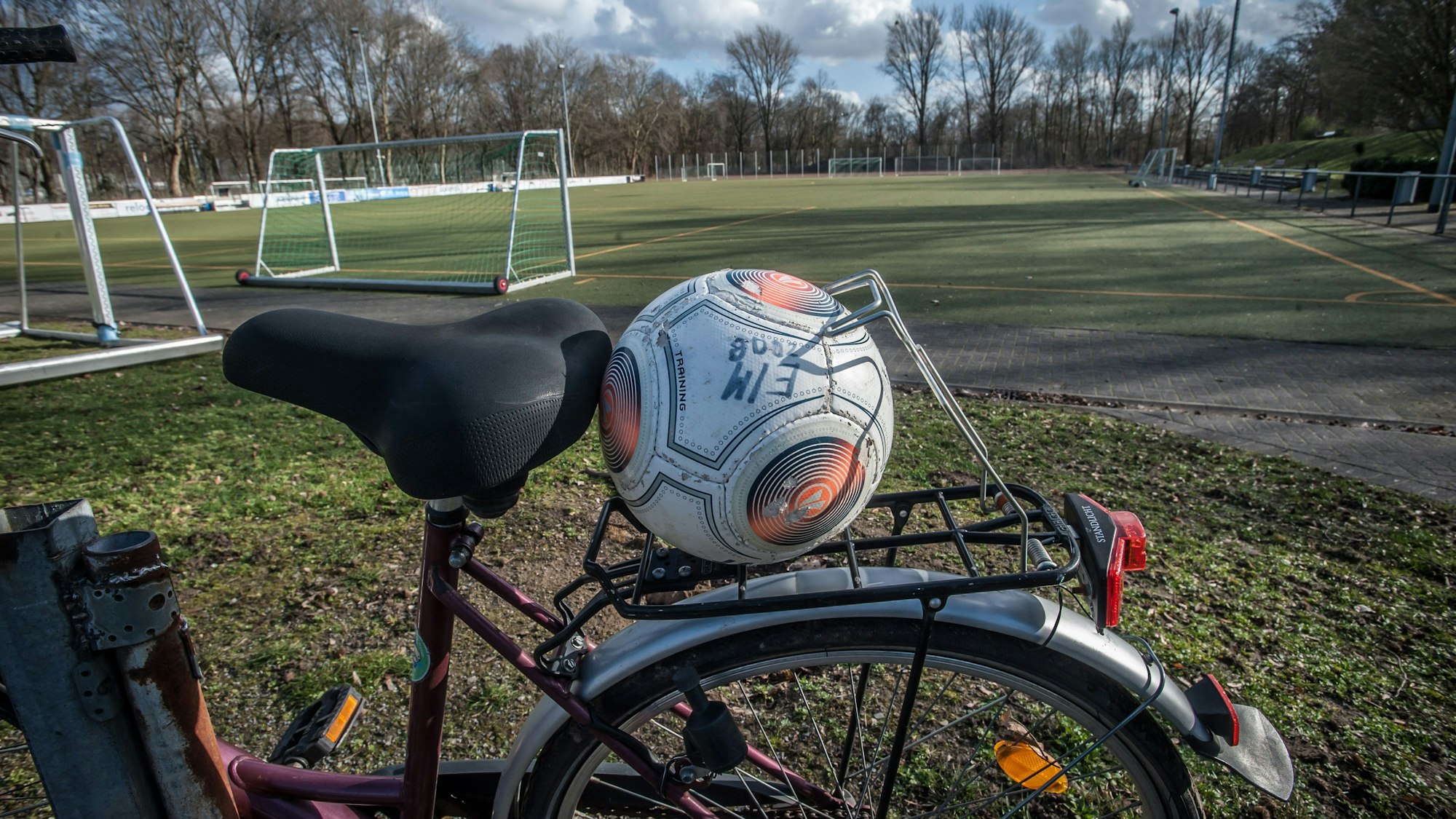 Ein Fußball klemmt auf dem Gepäckträger eines Fahrrads, das auf dem Sportplatz an der Tannenbergstraße steht.