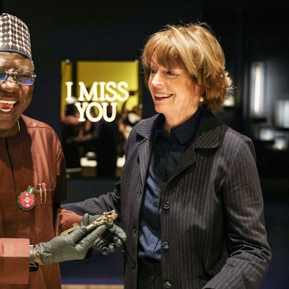 Henriette Reker, Oberbürgermeisterin von Köln, übergibt einem freudig lachenden Abba Isa Tijani, Generaldirektor der Nationalen Kommission für Museen und Monumente, symbolisch einen bronzenen Schlüssel aus dem Königreich Benin.