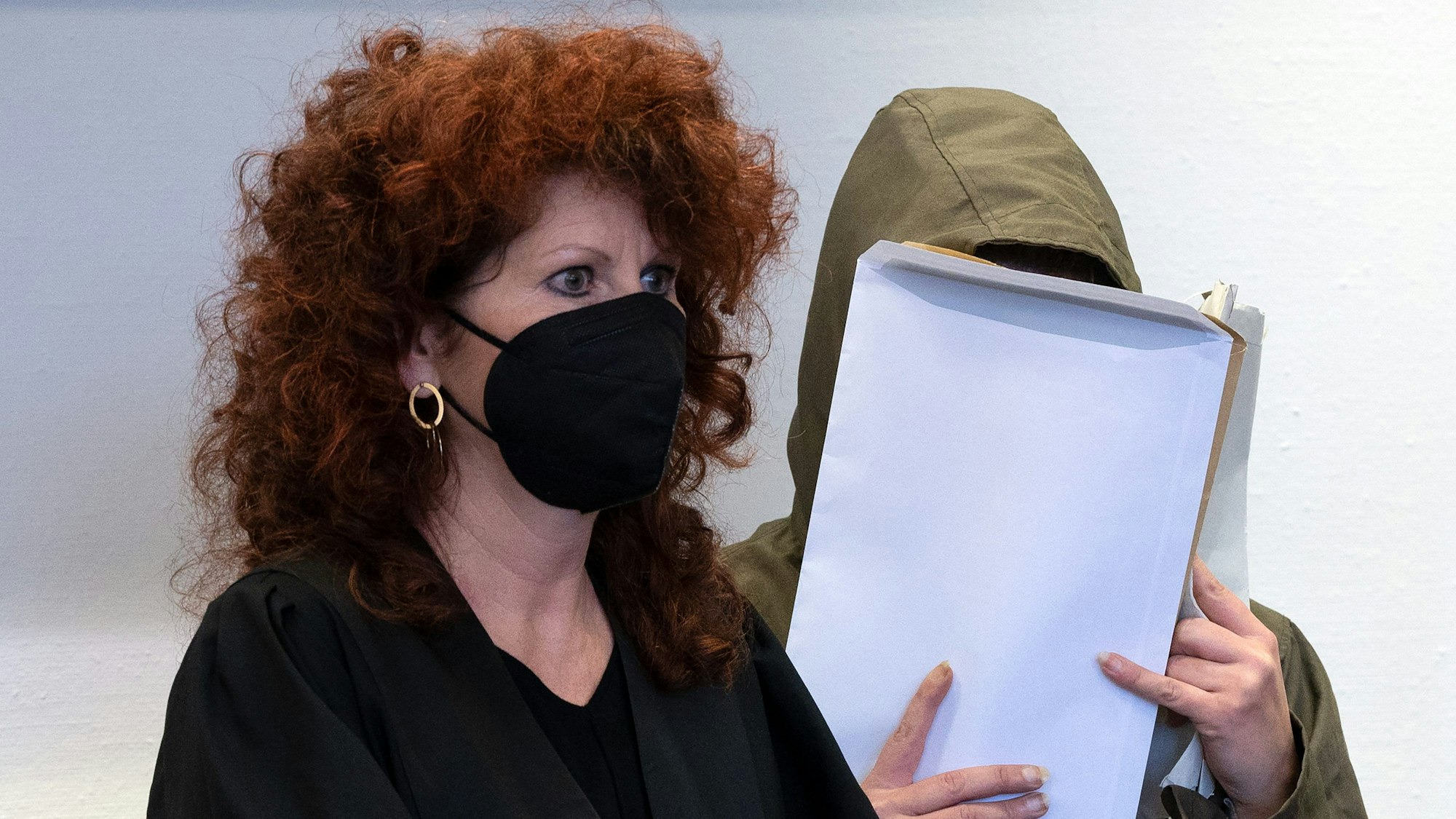 Die Angeklagte wartet mit ihrer Verteidigerin Barbara Schafgan-Herrmann, dass der Prozess im Landgericht Köln beginnt. Sie schirmt ihr Gesicht mit einem Umschlag ab.