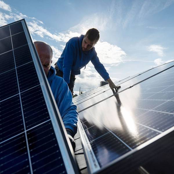 Techniker montieren Photovoltaikmodule auf dem Dach eines Wohnhauses.