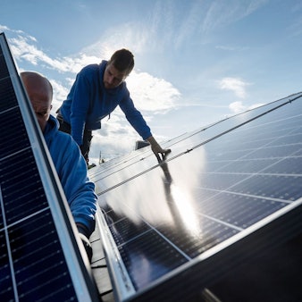 Techniker montieren Photovoltaikmodule auf dem Dach eines Wohnhauses.