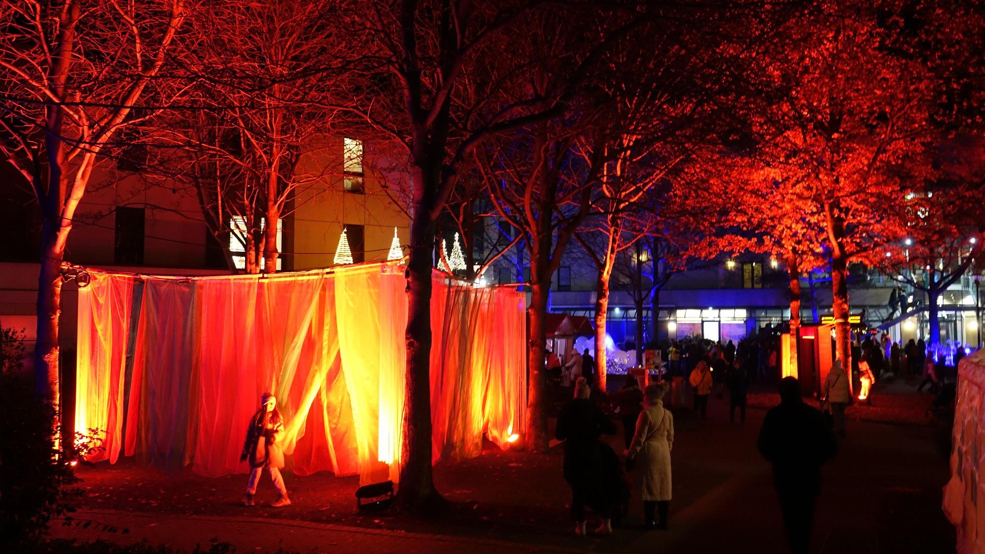 Aufgespannte Tücher erstrahlen in rot-goldenem Licht.
