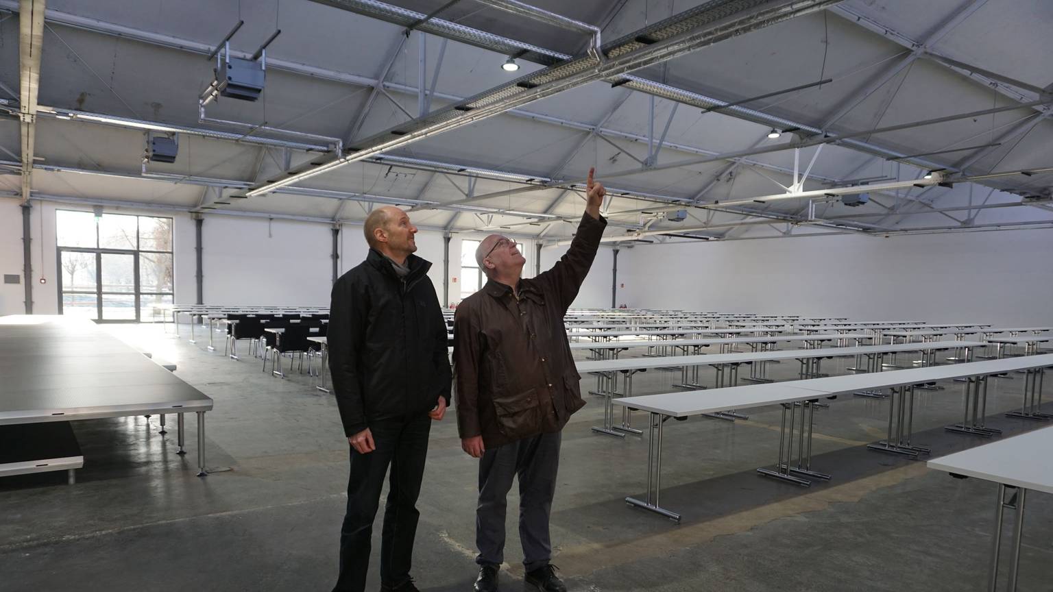 Zwei Männer, Jürgen Huthmacher (l.) und Christoph Stolzenberger, schauen sich das Dach der Veranstaltungshalle an.