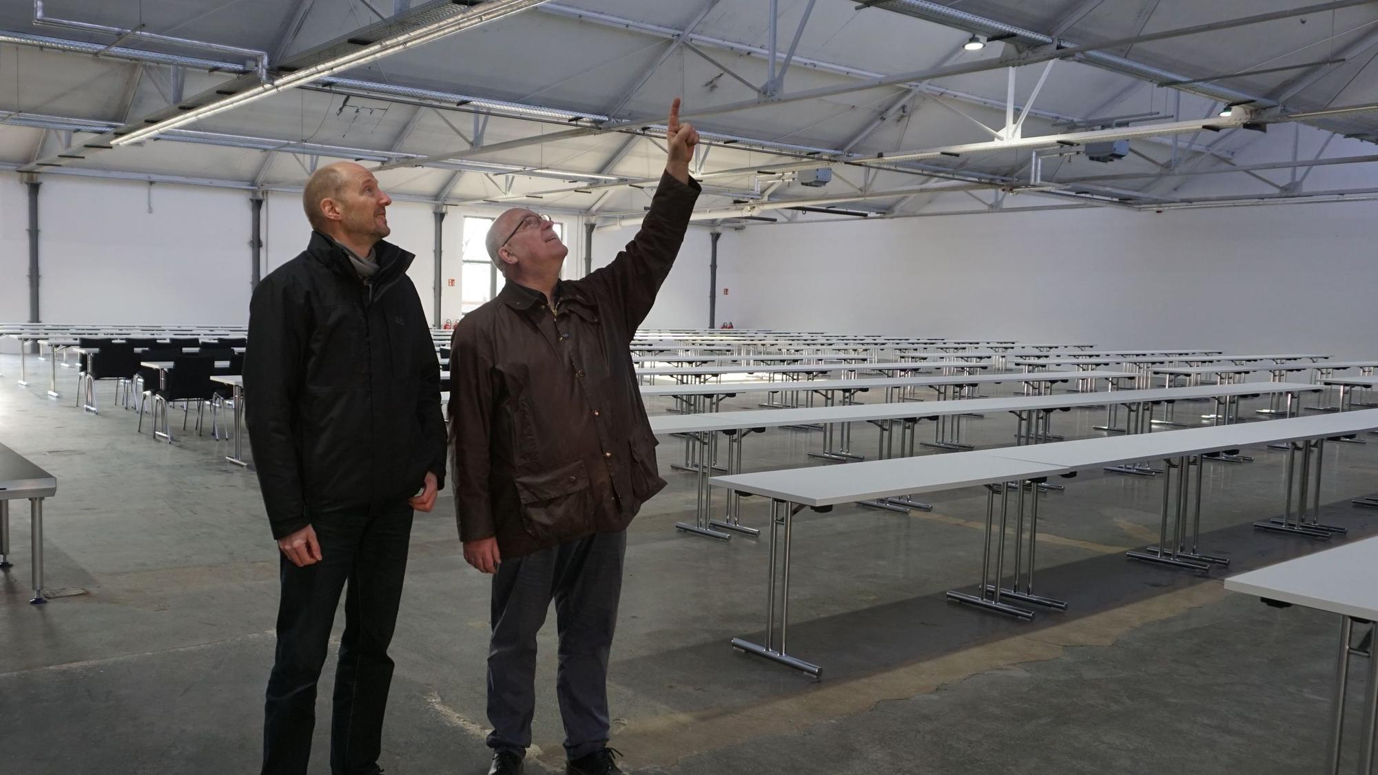 Zwei Männer, Jürgen Huthmacher (l.) und Christoph Stolzenberger, schauen sich das Dach der Veranstaltungshalle an.