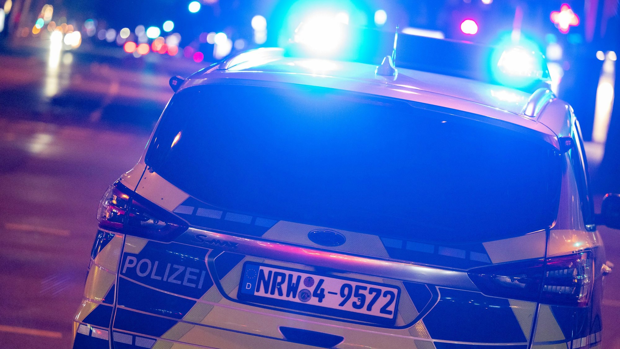 Ein Polizeiwagen fährt mit Blaulicht bei Nacht auf den Straßen.