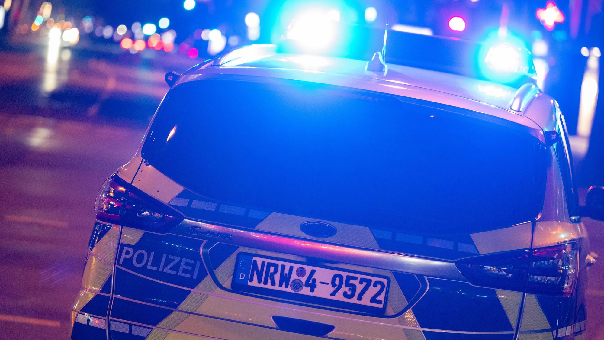 Ein Polizeiauto fährt nachts mit Blaulicht auf einer Straße.