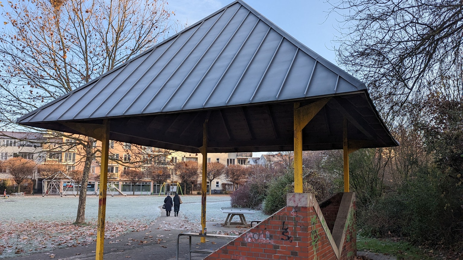 Ein Pavillon steht im Hof. Hinten laufen zwei Frauen.