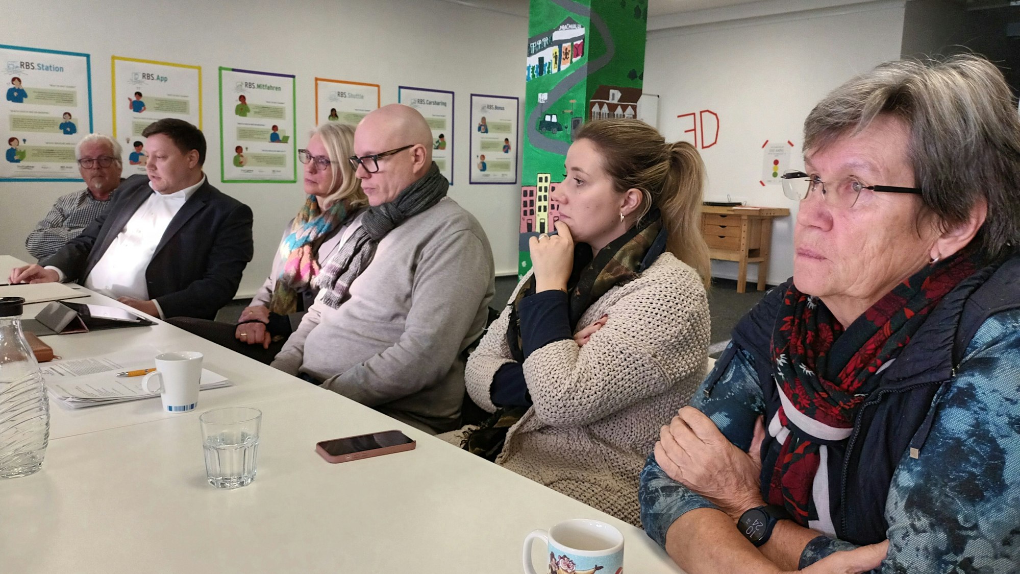 Drei Frauen und drei Männer sitzen zusammen am Tisch.