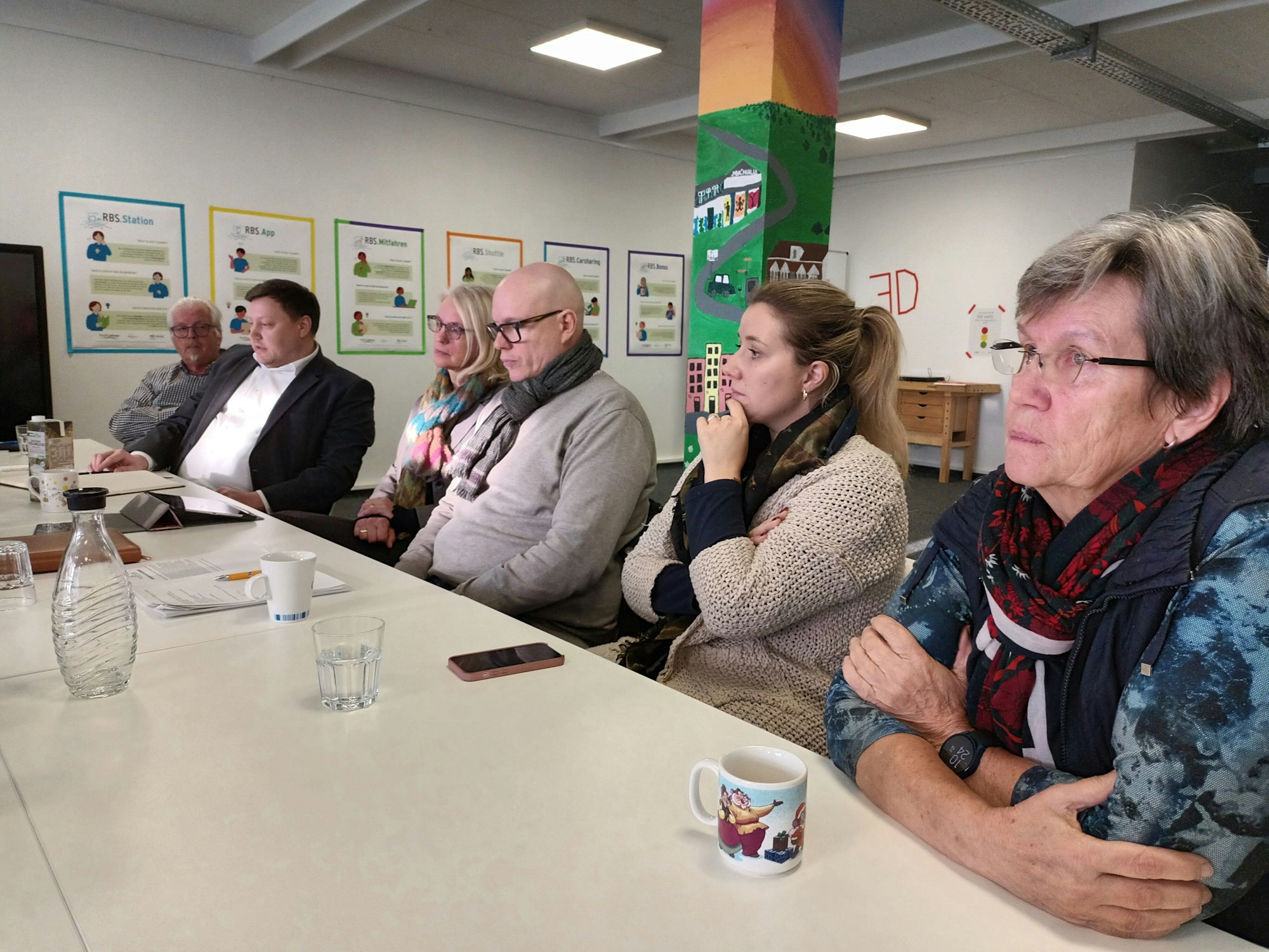 Drei Frauen und drei Männer sitzen am Tisch