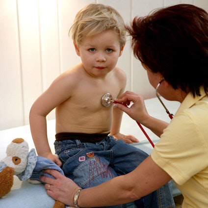 Eine Kinderärztin aus Frankfurt untersucht in ihrer Praxis einen kleinen Jungen mit einem Stethoskop.