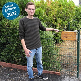 Djordje Atlialp steht vor einem Gartenzaun. Ein Schild daran trägt die Aufschrift „Wikelgasse“.