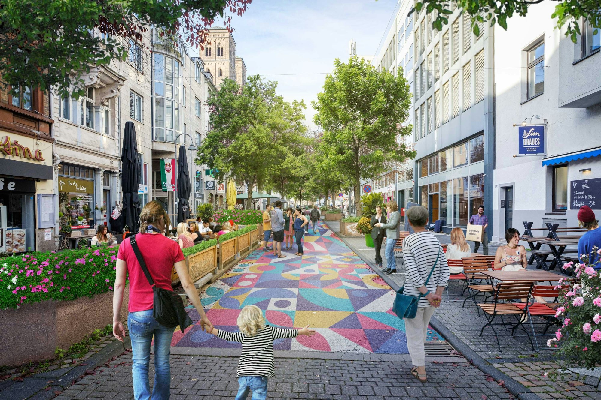 Der große Asphalt auf der Deutzer Freiheit ist bunt angemalt. Fußgänger schlendern über die Straße. Außengastronomie auf ehemaligen Parkplätzen am Straßenrand.