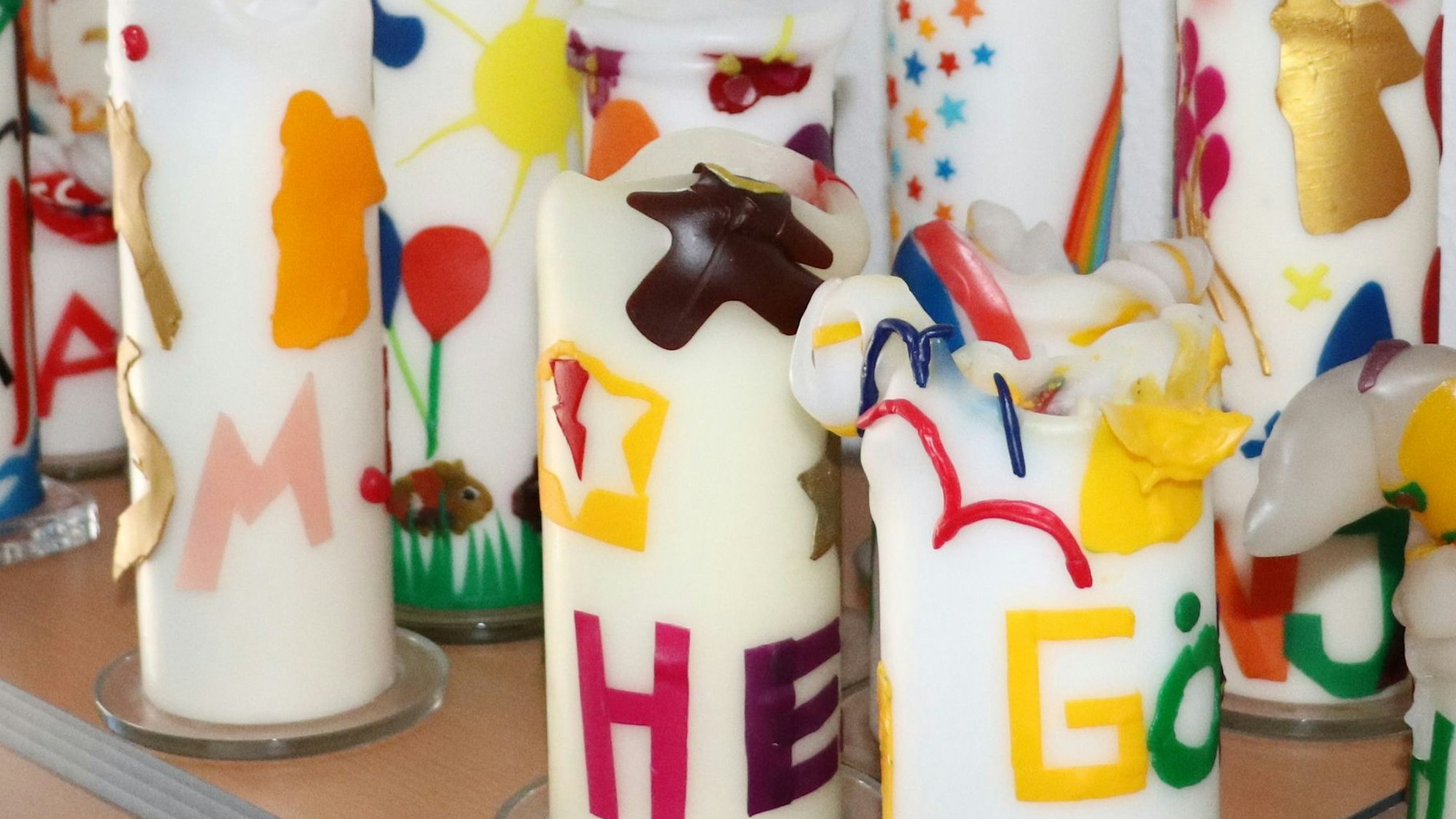 Bunte Kerzen stehen auf einer Ablage, sie erinnern an verstorbene Kinder.