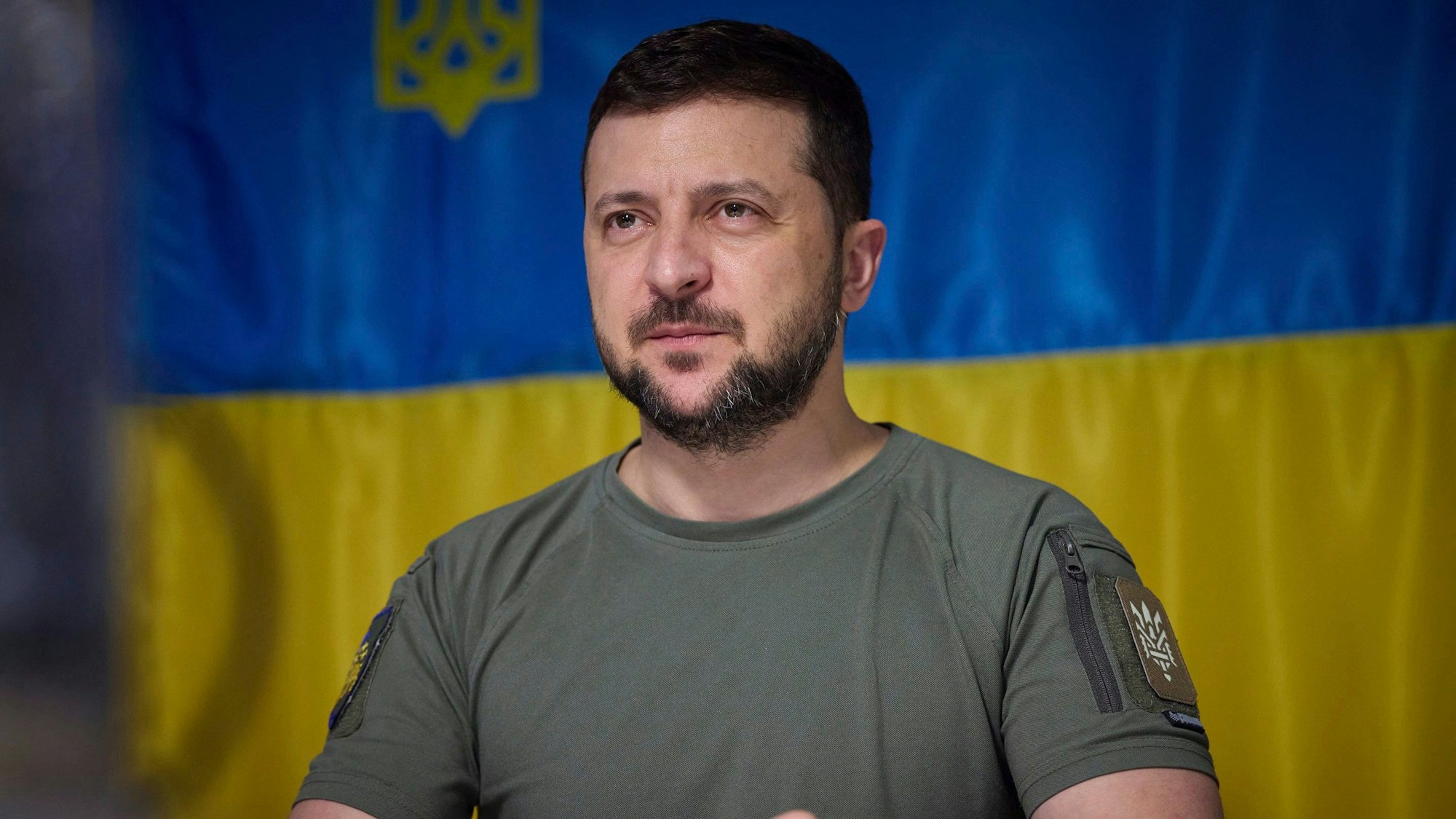 Wolodymyr Selenskyj, Präsident der Ukraine, spricht bei einem Besuch in der vom Krieg betroffenen Oblast Dnipropetrowsk zu Militärvertretern. Hinter ihm ist die Ukraine-Flagge.
