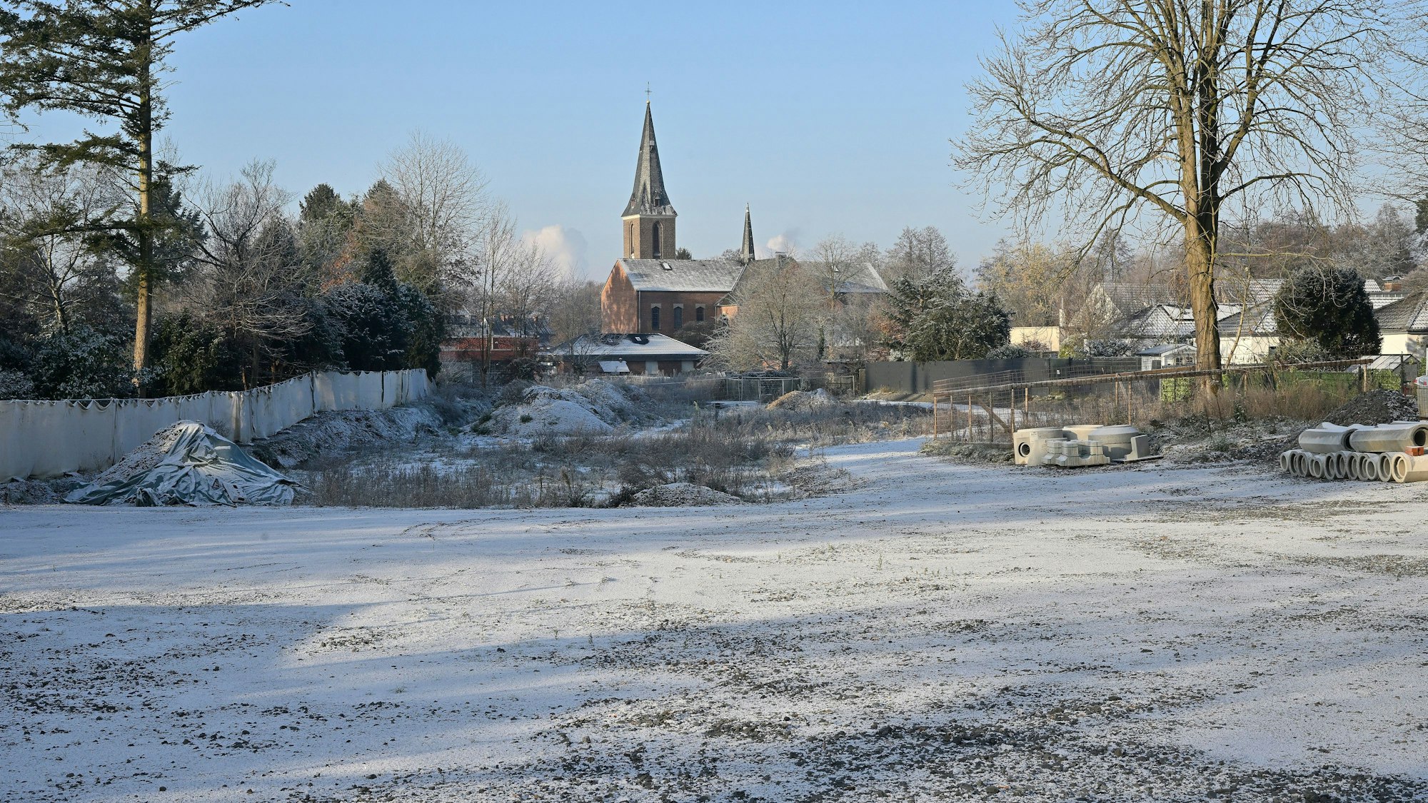 Das Baugrundstück im Schnee, im Hintergrund die Kirche.