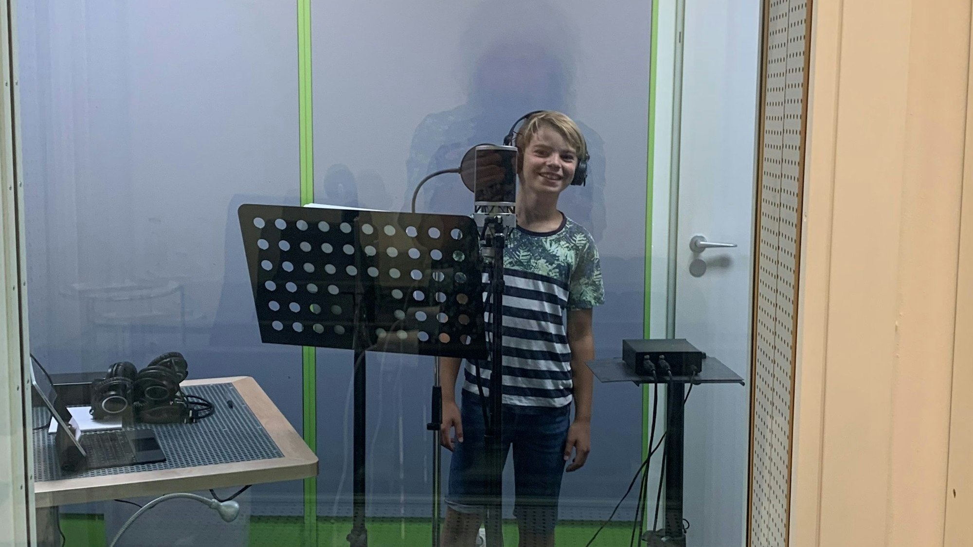 Theo von der Domsingschule steht mit Kopfhörern vor einem großen Mikrofon im Kölner Tonstudio.