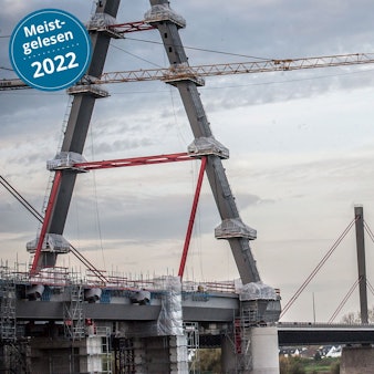 Die zwei neuen Pylone der Leverkusener Brücke sind im Vordergrund zu sehen. Es ist eine große Baustelle. Im Hintergrund ragt der alte Pylon in den leicht bedeckten Himmel.