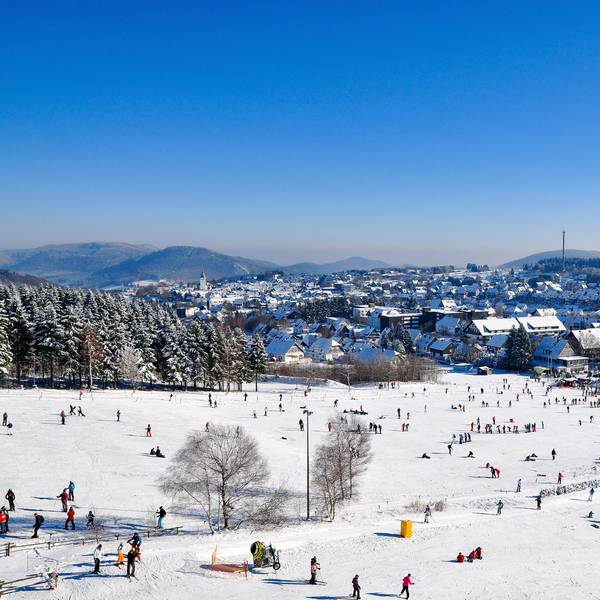 Winterberg liegt im Tal, während Skifahrer sich auf der Piste tummeln.