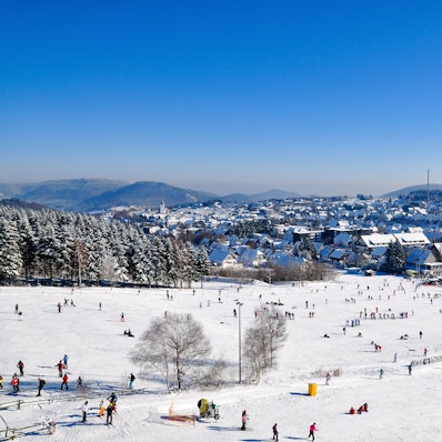 Winterberg liegt im Tal, während Skifahrer sich auf der Piste tummeln.