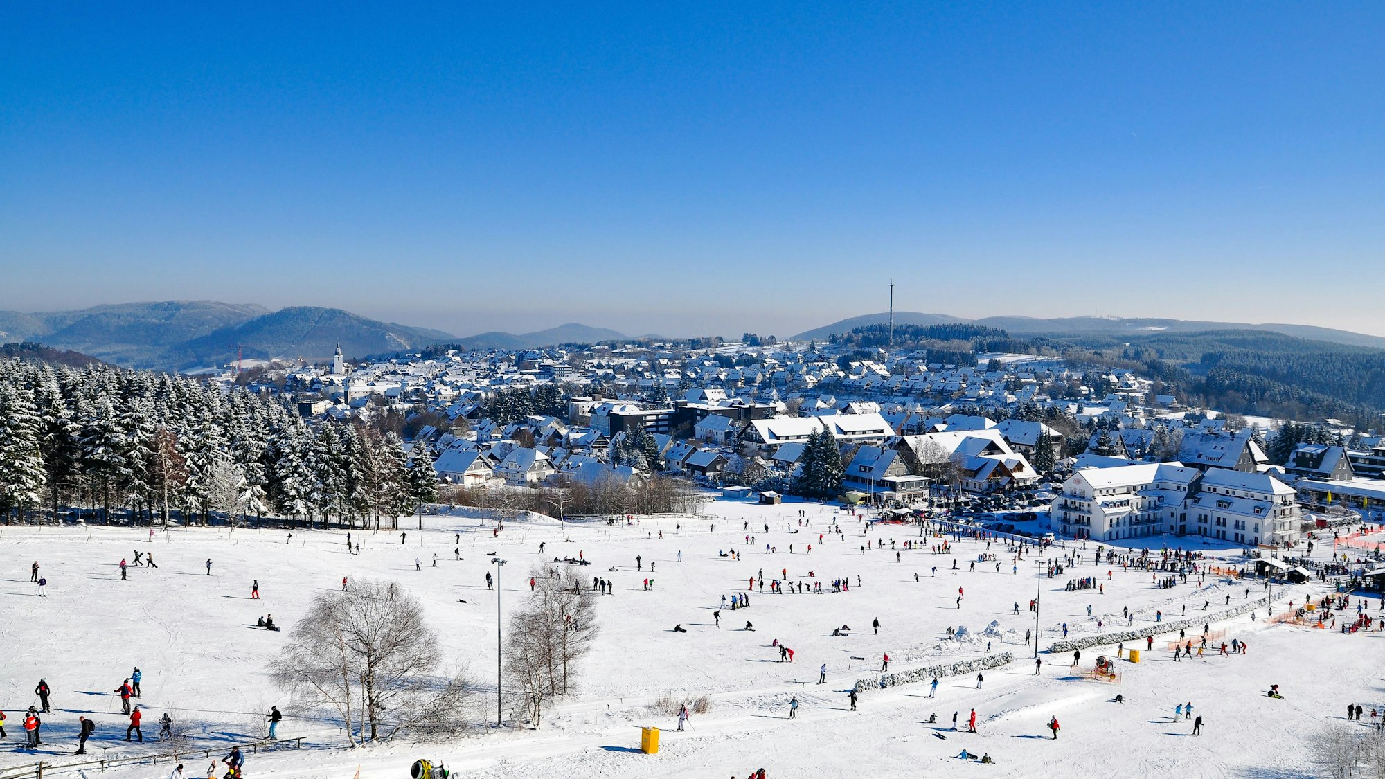 Winterberg liegt im Tal, während Skifahrer sich auf der Piste tummeln.