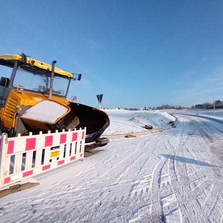 Noch führt die neue Straße bei Birk ins Nirgendwo. Sie soll die Neubauten an den Ort anbinden. Links ein Bagger hinter einer Straßenabsperrung. Mittig im Bild eine Straße im Schnee, die ins nichts führt.
