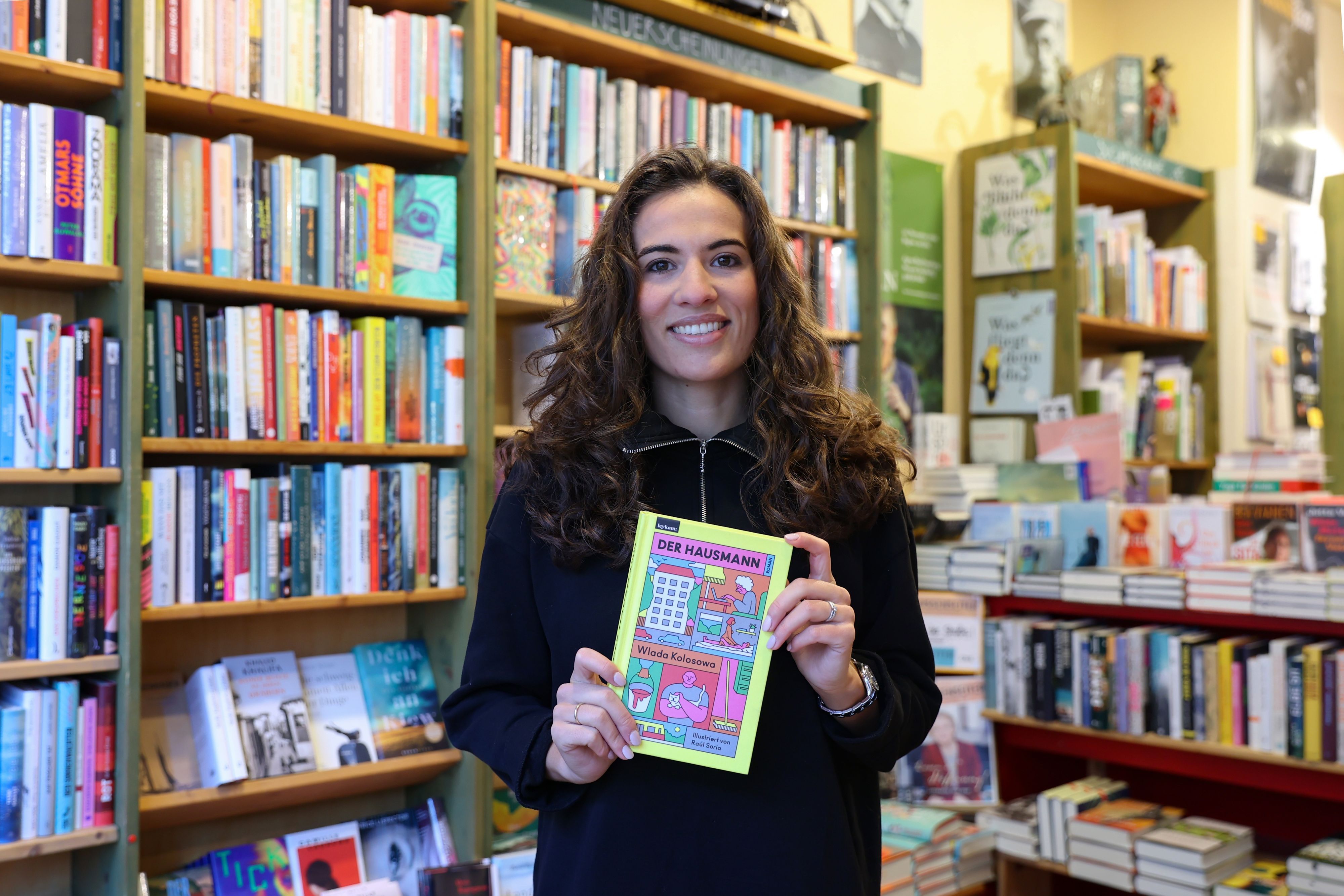 Mona Ameziane steht mit ihrem Lieblingsbuch 2022 in der Hand in der Agnes Buchhandlung.