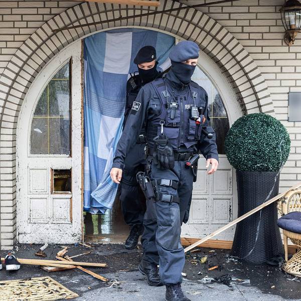 Polizisten verlassen in Leverkusen eine Villa durch eine zerstörte Eingangstür nach Durchsuchungen im Bereich der Clankriminalität.