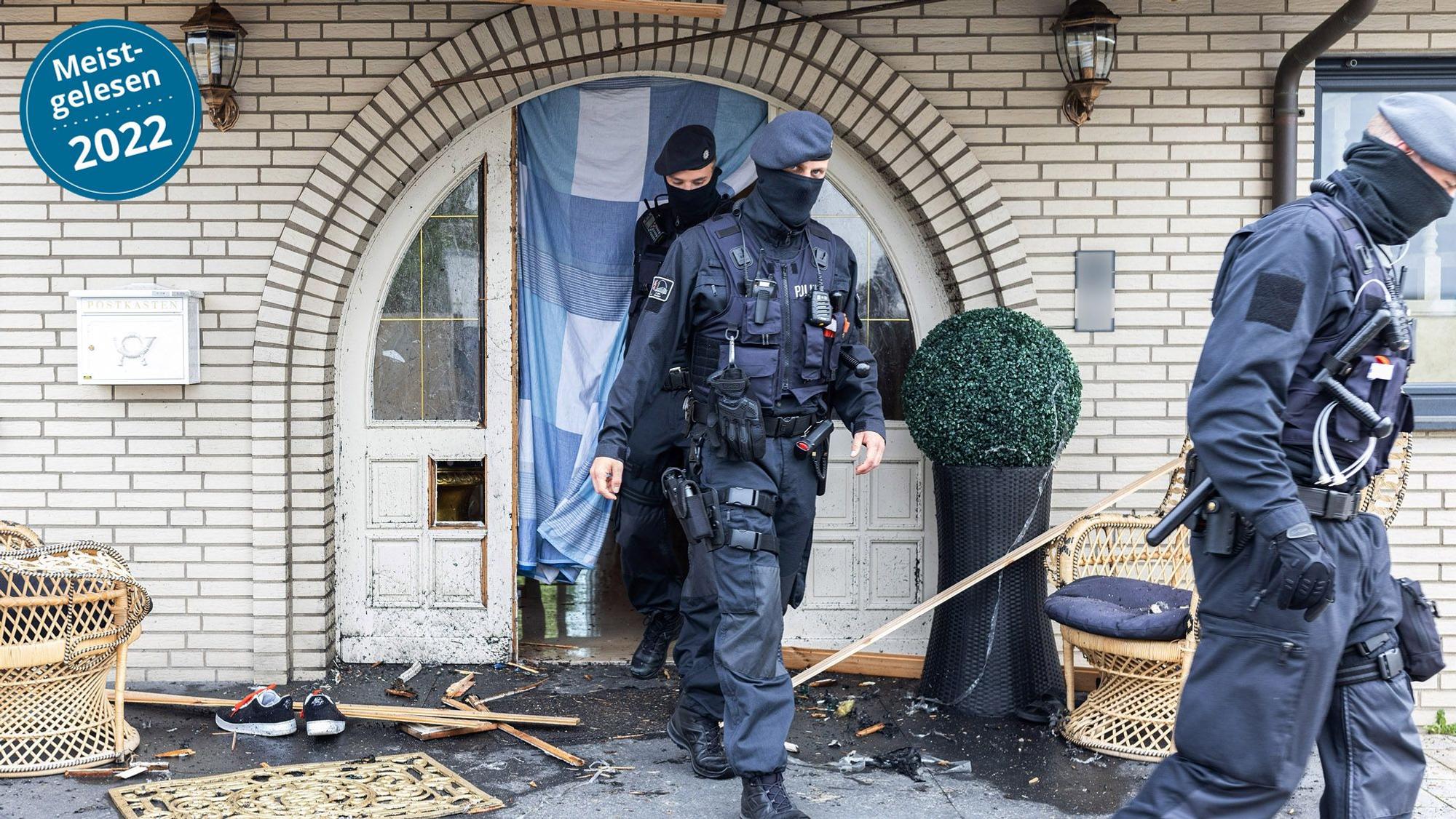 Polizisten verlassen in Leverkusen eine Villa durch eine zerstörte Eingangstür nach Durchsuchungen im Bereich der Clankriminalität.