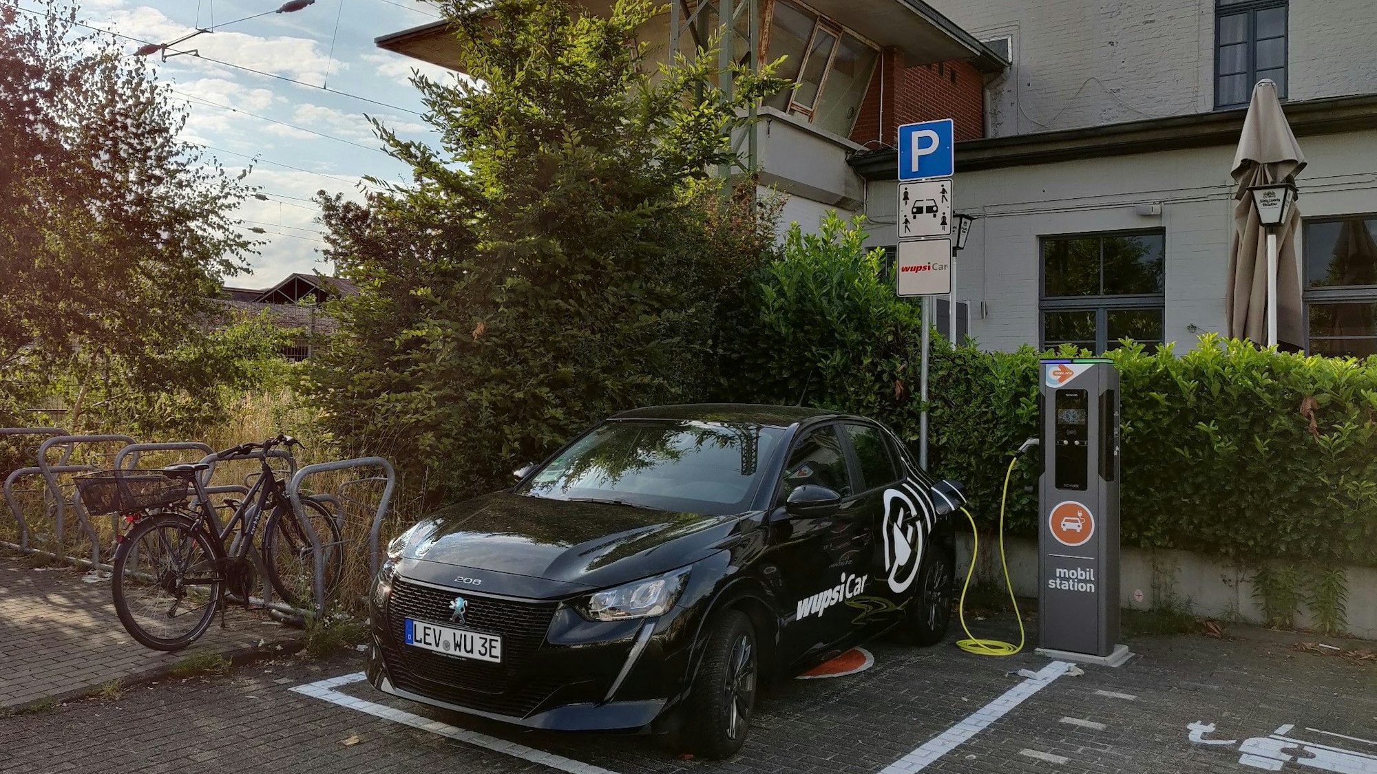 Mobilstation am Bahnhof, wo ein Elektro-Auto an der Ladesäule Strom tankt.