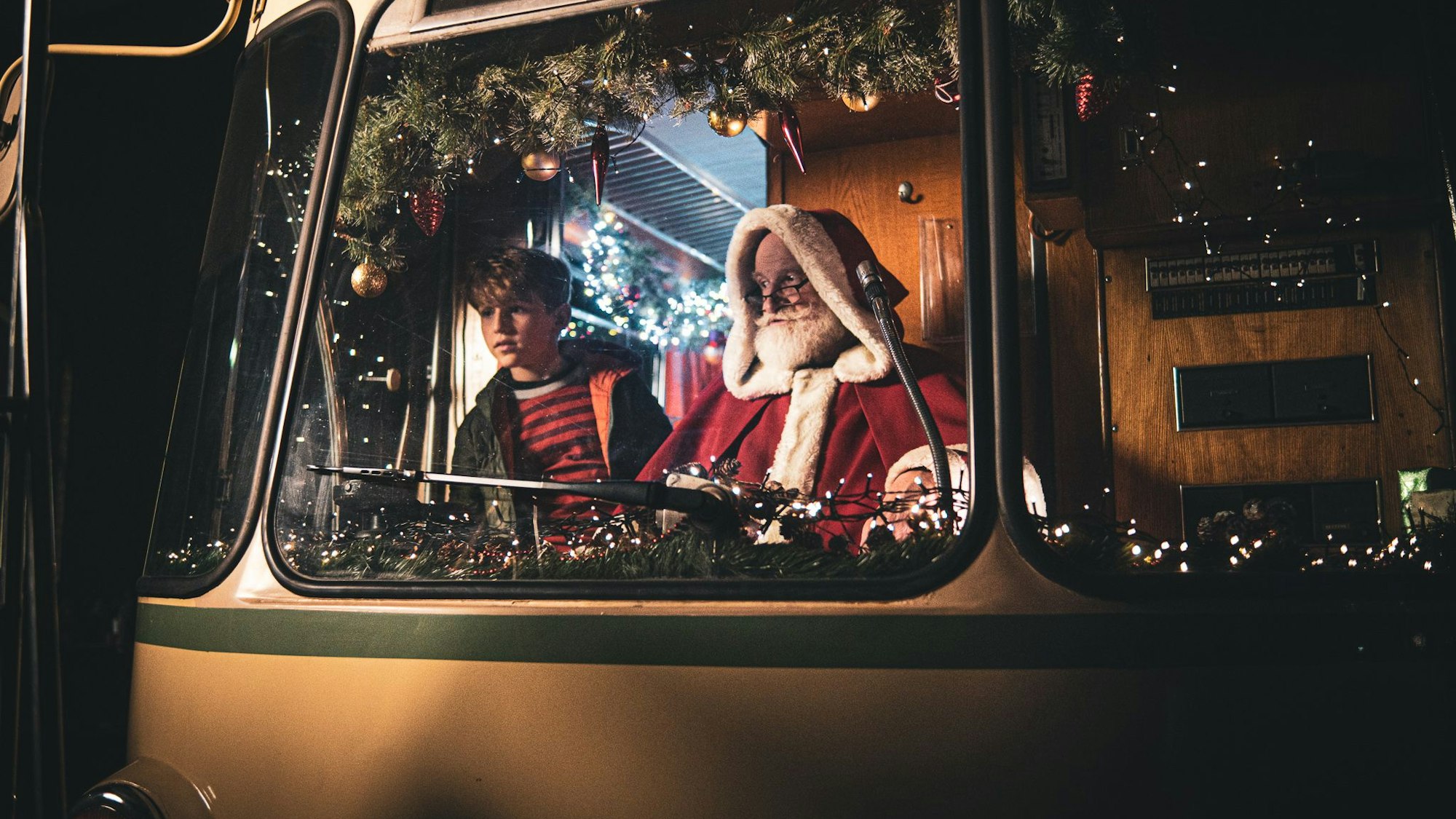Der Weihnachtsmann und ein Junge sitzen zusammen in der Fahrerkabine einer historischen Stadtbahn der KVB.