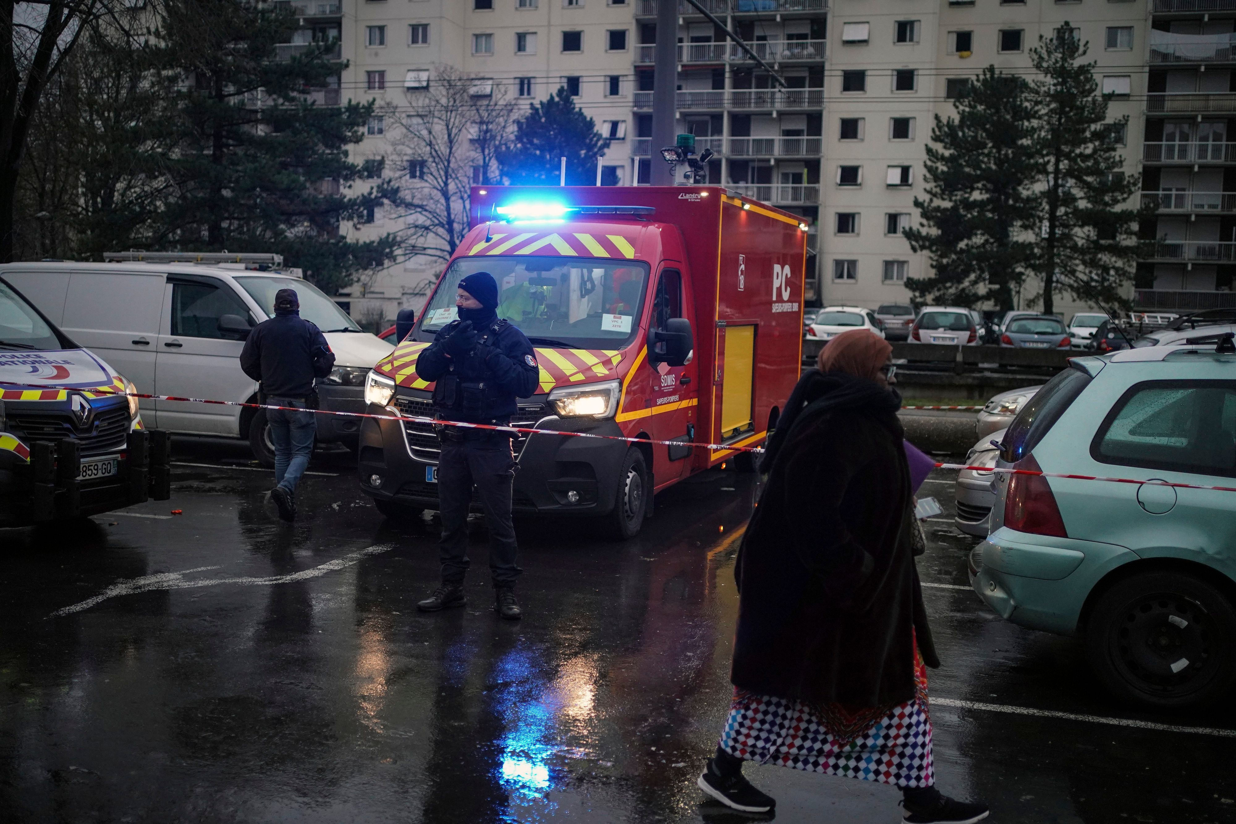 Ein Polizeibeamter steht neben einem Feuerwehrauto vor den Wohnhäusern im Viertel Le Mas du Taureaum in Vaulx-en-Velin, außerhalb von Lyon.