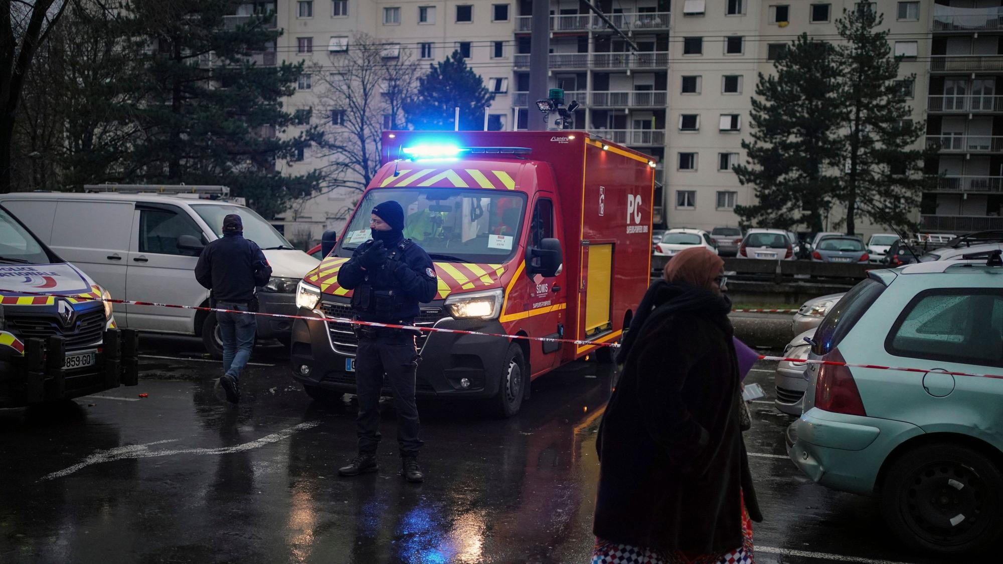 Ein Polizeibeamter steht neben einem Feuerwehrauto vor den Wohnhäusern im Viertel Le Mas du Taureaum in Vaulx-en-Velin, außerhalb von Lyon.